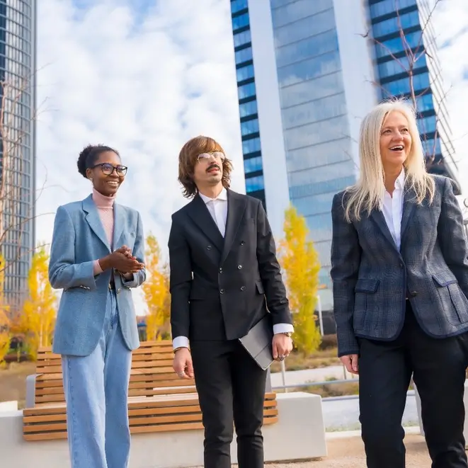 Three business professionals talking outside office buildings.